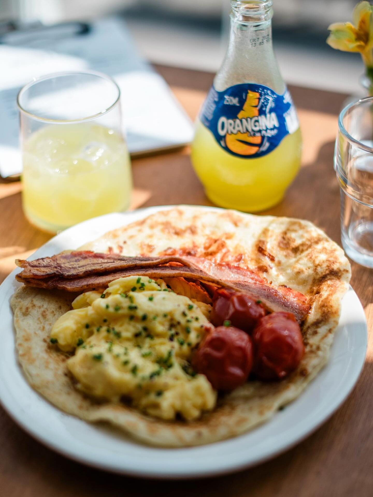 A breakfast plate with eggs, bacon and orange soda